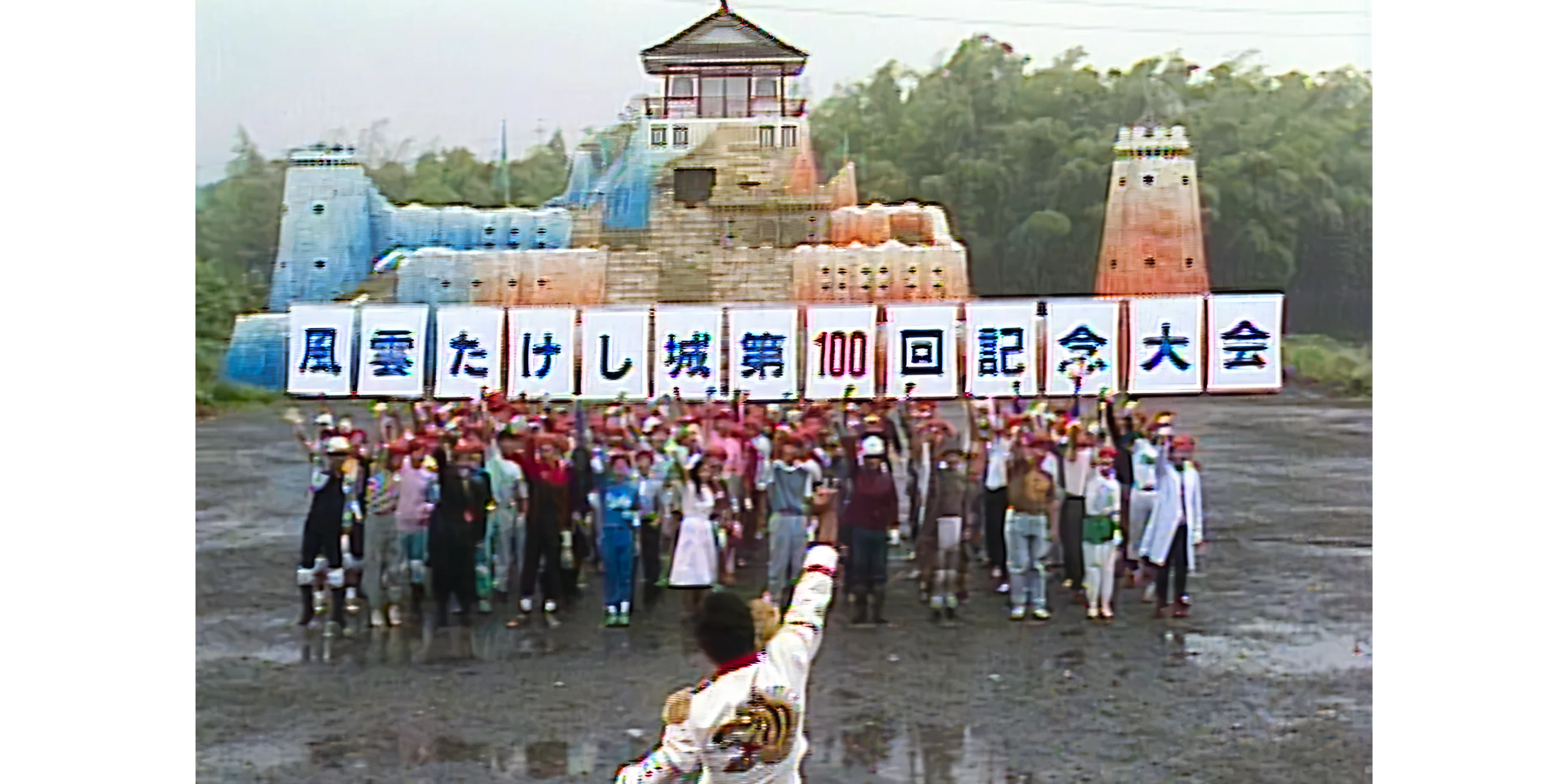 100 contestants stand in front of Takeshi's Castle as the General faces them raising his fist in the air.